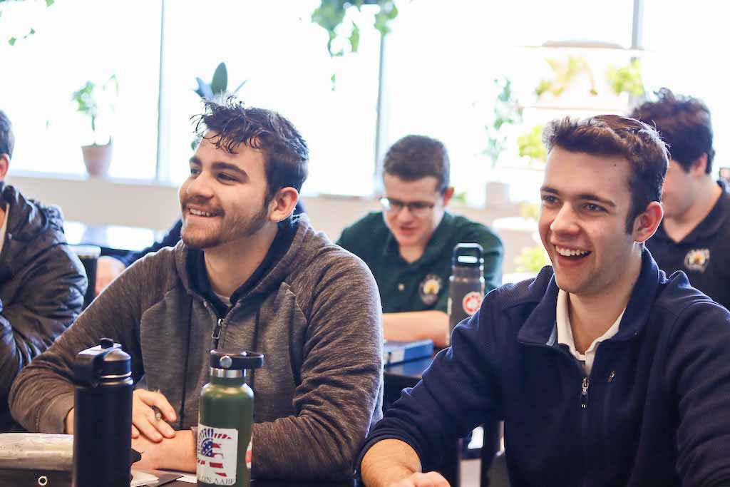 Seniors2023 Three smiling boys working on an in class assignment